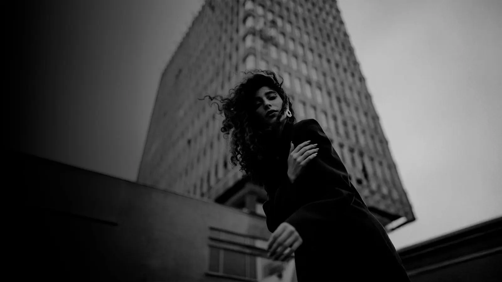 Mujer frente a un edificio alto, en blanco y negro